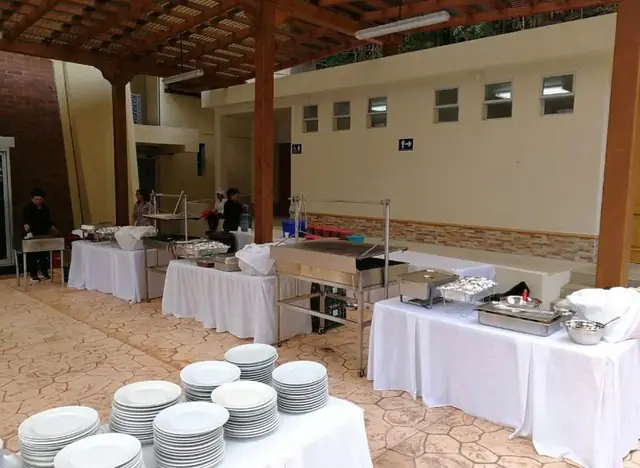 Montaje de buffet en patio con mesas, vajilla y calentadores